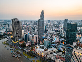 beautiful sunset over Ho Chi Minh city skyline and Saigon river, green tropical park and financial downtown district with tall skyscraper towers, Vietnam aerial drone view