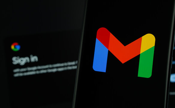 Dhaka, Bangladesh- 16 March 2025: Gmail logo is displayed on a smartphone screen, with the gmail login page visible on a computer screen in the background.