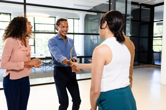 Diverse business team greeting each other with handshakes in modern office