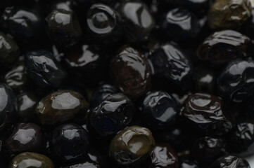 Dark, glossy stones captured in close-up, revealing a rich texture and intricate details under soft...