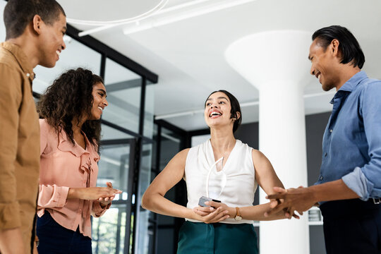 Diverse business team laughing and collaborating in modern office environment