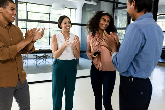 Diverse business team clapping and celebrating success in modern office