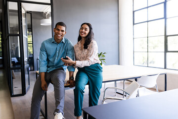 Smiling diverse colleagues in modern office discussing project, enjoying teamwork success