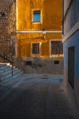 cozy street of ancient European town, sunset over historic buildings, sun falling on old walls