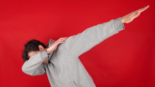 Happy man in casual making dab arms gesture on blank red studio background, funny white guy dabbing moving in internet meme pose celebrating victory having fun, dance school or triumph concept