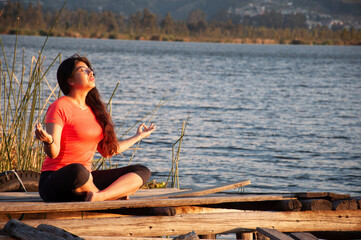A Serene Woman Meditating Calmly by the Peaceful Water Beneath a Beautiful Sunset Sky