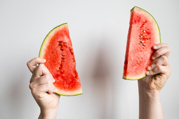 Hands holding watermelon slices against white background