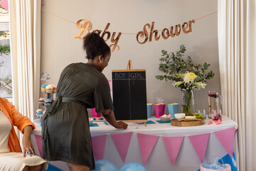 Decorating baby shower table with pink and blue theme, preparing for celebration, at home