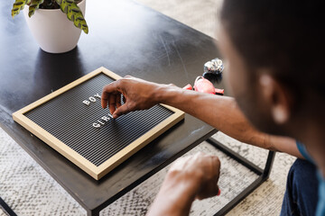 Baby shower, Man arranging letters on board at home, preparing for celebration message