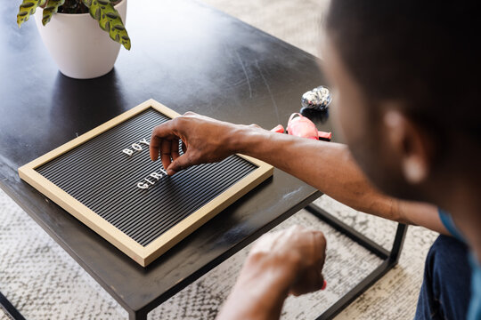 Baby shower, Man arranging letters on board at home, preparing for celebration message