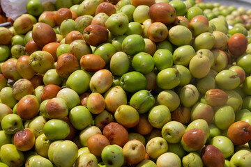 A bountiful heap of jujube fruits displays vibrant green hues with soft brown accents, revealing...