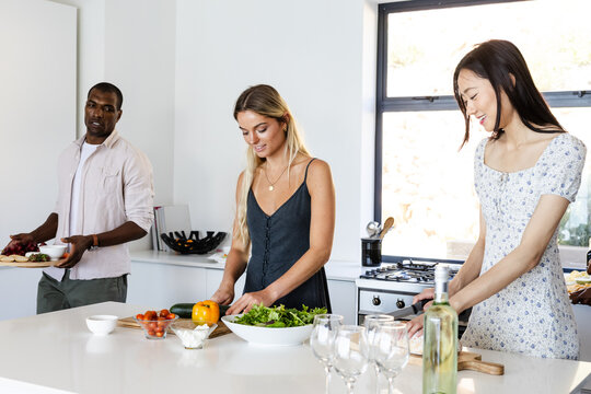 Housewarming, Diverse friends preparing fresh salad and appetizers together in modern kitchen
