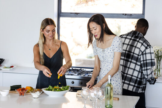 Housewarming, Diverse friends preparing fresh salad together in modern kitchen, enjoying cooking tim