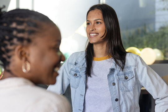 Smiling diverse friends enjoying conversation at home during celebration, feeling happy