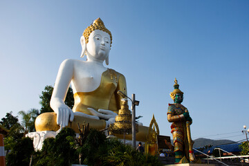 Fototapeta premium Big golden buddha image statue of Wat Phra That Doi Kham Temple for thai people and foreign travelers travel visit and respect praying at Mae Hia city on November 10, 2020 in Chiang Mai, Thailand