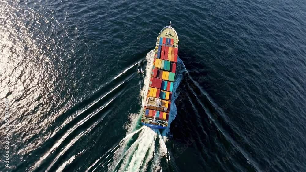 Poster aerial video captures a colorful cargo ship navigating through deep blue waters, showcasing a top-do