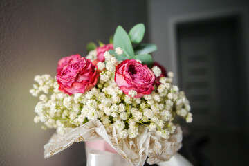 Beautifully arranged bouquet of pink roses and white fillers elegantly displayed on a dark surface with soft lighting