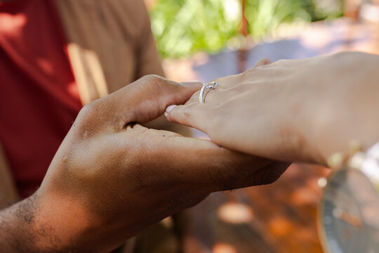 Romantic proposal moment as man gently places engagement ring on woman's finger - Powered by Adobe