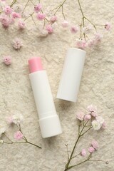 Lip balm and gypsophila flowers on white textured background, flat lay