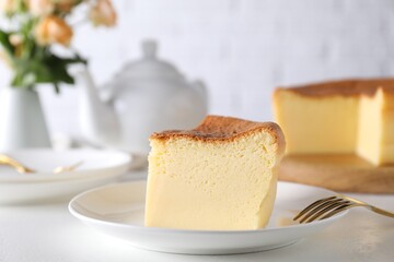 Piece of tasty Japanese Castella sponge cake and fork on white table, closeup