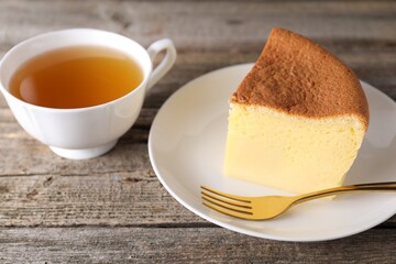 Pieces of tasty Japanese Castella sponge cake, tea and fork on wooden table, closeup