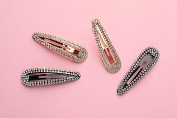 Different hair clips on pink background, flat lay