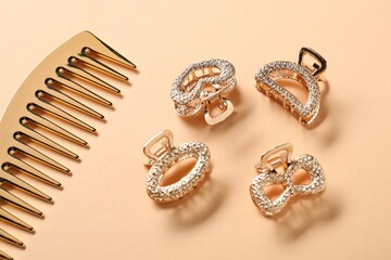 Different hair clips and comb on beige background, flat lay