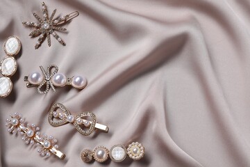 Beautiful hair clips on beige fabric, flat lay. Space for text