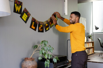African American man hanging welcome banner at home, preparing for celebration, at home