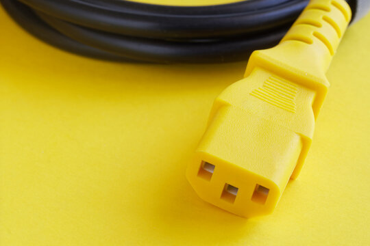 A close-up of a yellow C13 power connector cable on a bright background. Perfect for illustrating computer or appliance power supply and safety concepts. Photo