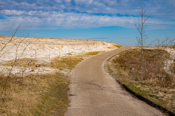 Winding road through coastal dunes under blue sky