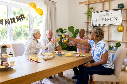 Celebrating retirement, senior diverse friends making cheerful toast together at home