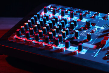 Professional mixing console on table in neon lights, closeup
