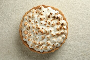 Delicious meringue pie on beige textured table, top view