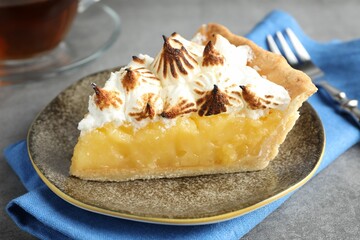 Piece of delicious pie with browned meringue on grey textured table, closeup