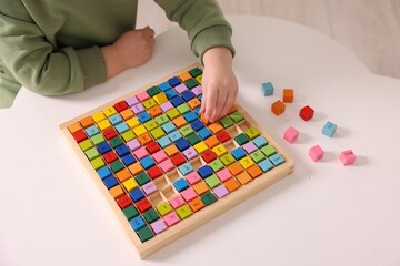 Fototapeta premium Motor skills development. Little boy playing with Times table tray indoors, closeup