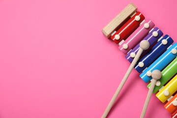 Colorful toy xylophone with mallets on pink background, top view. Space for text