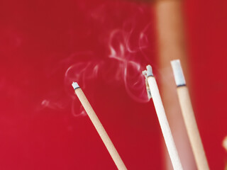 Burning incense with smoke on red background for religion or belief.  
