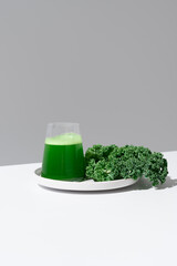 Batido de jugo de col rizada verde y hojas frescas de col rizada sobre fondo gris