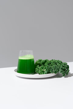 Batido de jugo de col rizada verde y hojas frescas de col rizada sobre fondo gris