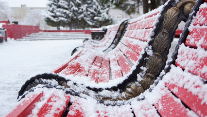 red park benches covered with snow