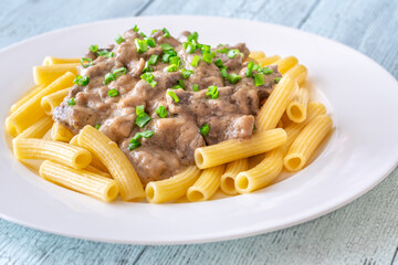 Beef stroganoff with rigatoni pasta, topped with fresh green onion garnish