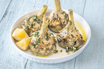Four Roman-style artichokes served on white plate, tender and beautifully seasoned