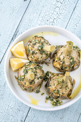 Four Roman-style artichokes served on white plate, tender and beautifully seasoned