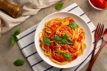 Spaghetti with fresh tomatoes sauce in white plate.topped with parmesan cheese and basil.Top view.