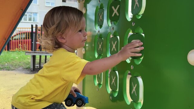 Happy child interacts with a colorful play wall that promotes sensory exploration, creativity, and interactive play in an outdoor playground, enhancing learning and fun