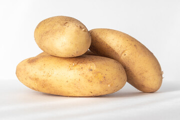 Young fresh potatoes with earth particles, organic potatoes, highlighted on a white background.