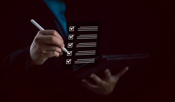 Digital checklist and task management concept. Businessman uses stylus on tablet to complete list items on virtual interface, improving productivity, focus, and efficient project planning.