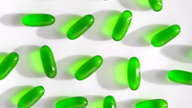 Vitamin e capsules kept on rotating disk. Close up of green vitamin e capsules on white surface.