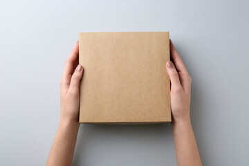 Woman with blank cardboard box on white background, top view. Mockup for design